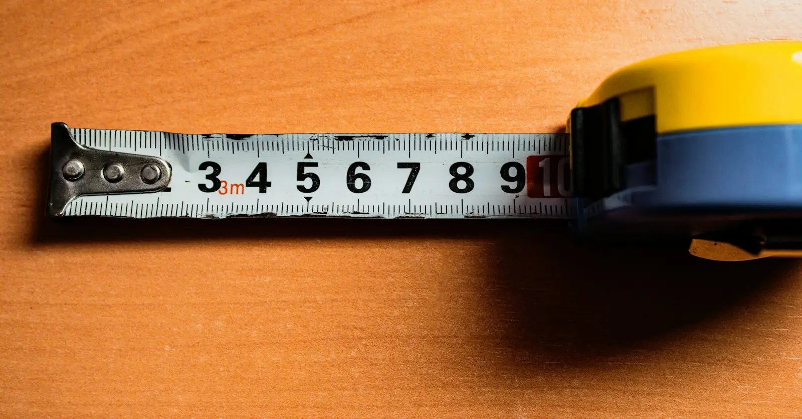 A tape measure extended across a wooden table