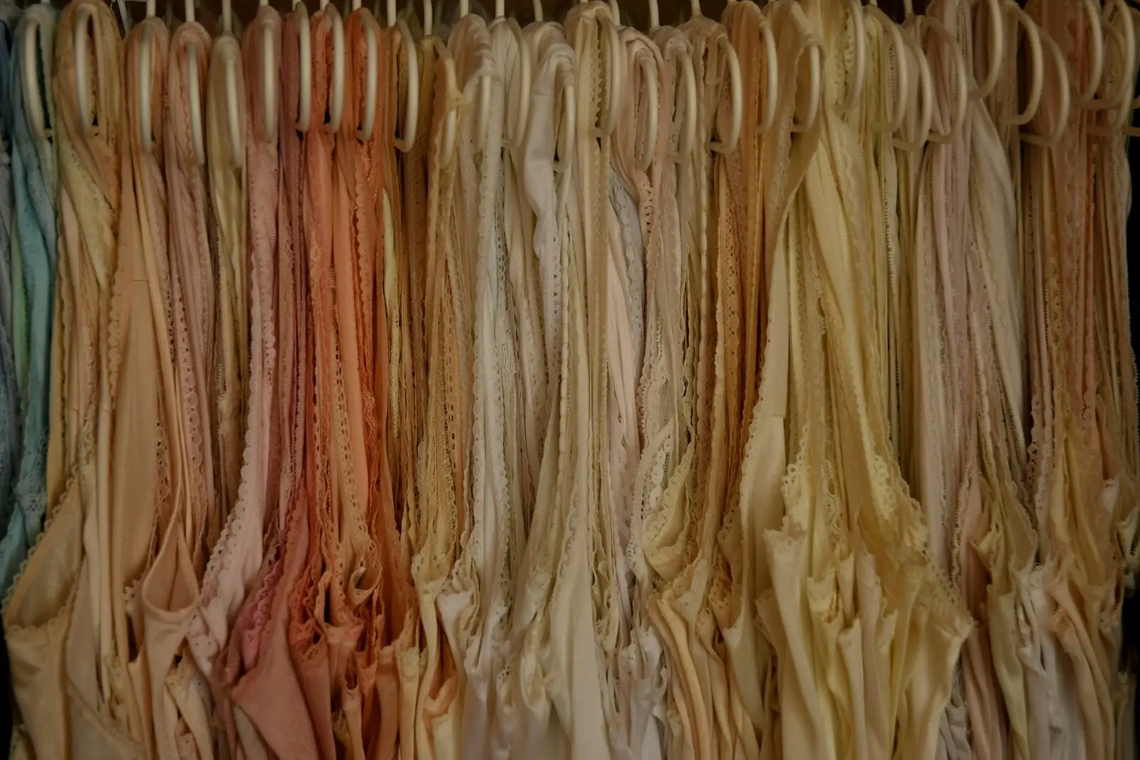 Rows of nude and blush bras hanging on hangers